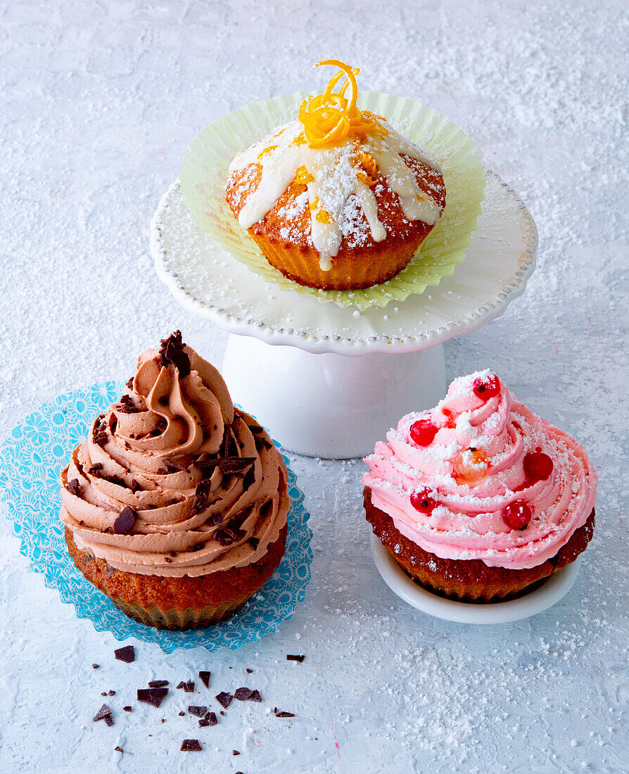 Drei verschiedene Cupcakes, mit Orangen, mit Johannisbeeren und mit Schoko