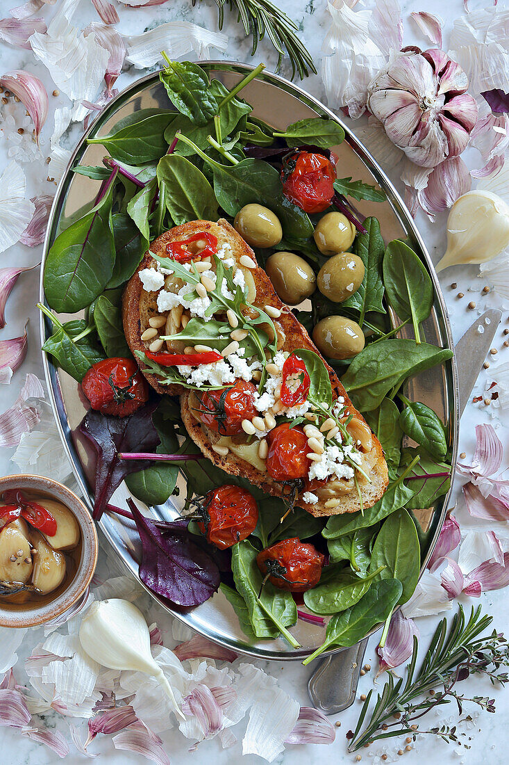 Toasted bread sandwich with garlic confit, cherry tomatoes, goat cheese, and pine nuts