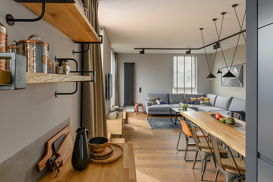 Open living space with kitchen, dining area, and lounge in muted grey tones and natural wood