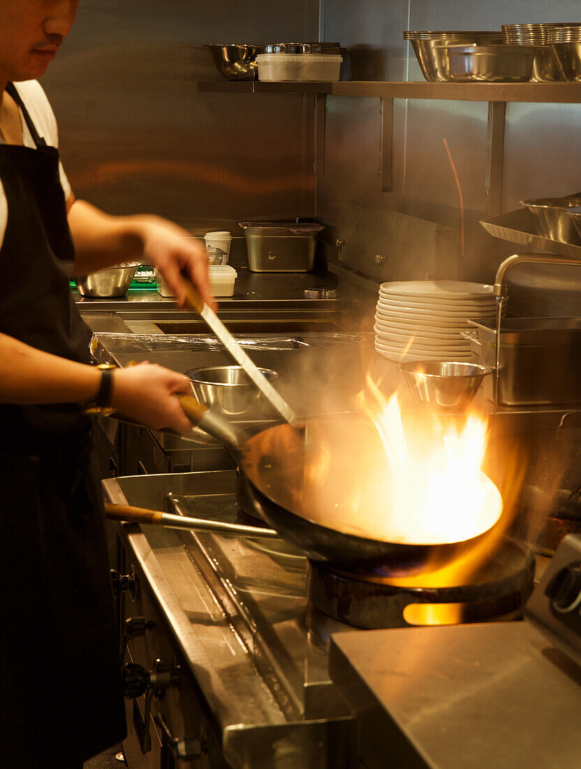 Koch mit Wok in der Restaurantküche