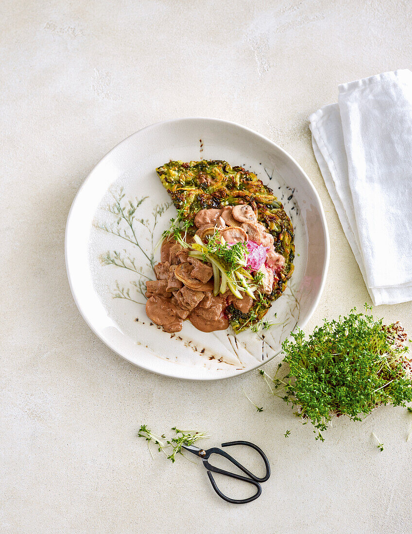 Veggie patty with savoy cabbage hash browns topped with 'Stroganoff-style' sauce