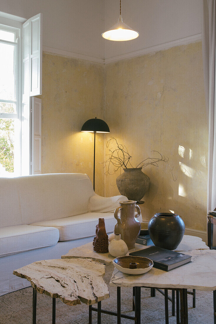 White upholstered sofa and floor lamp, table with marble top in the foreground