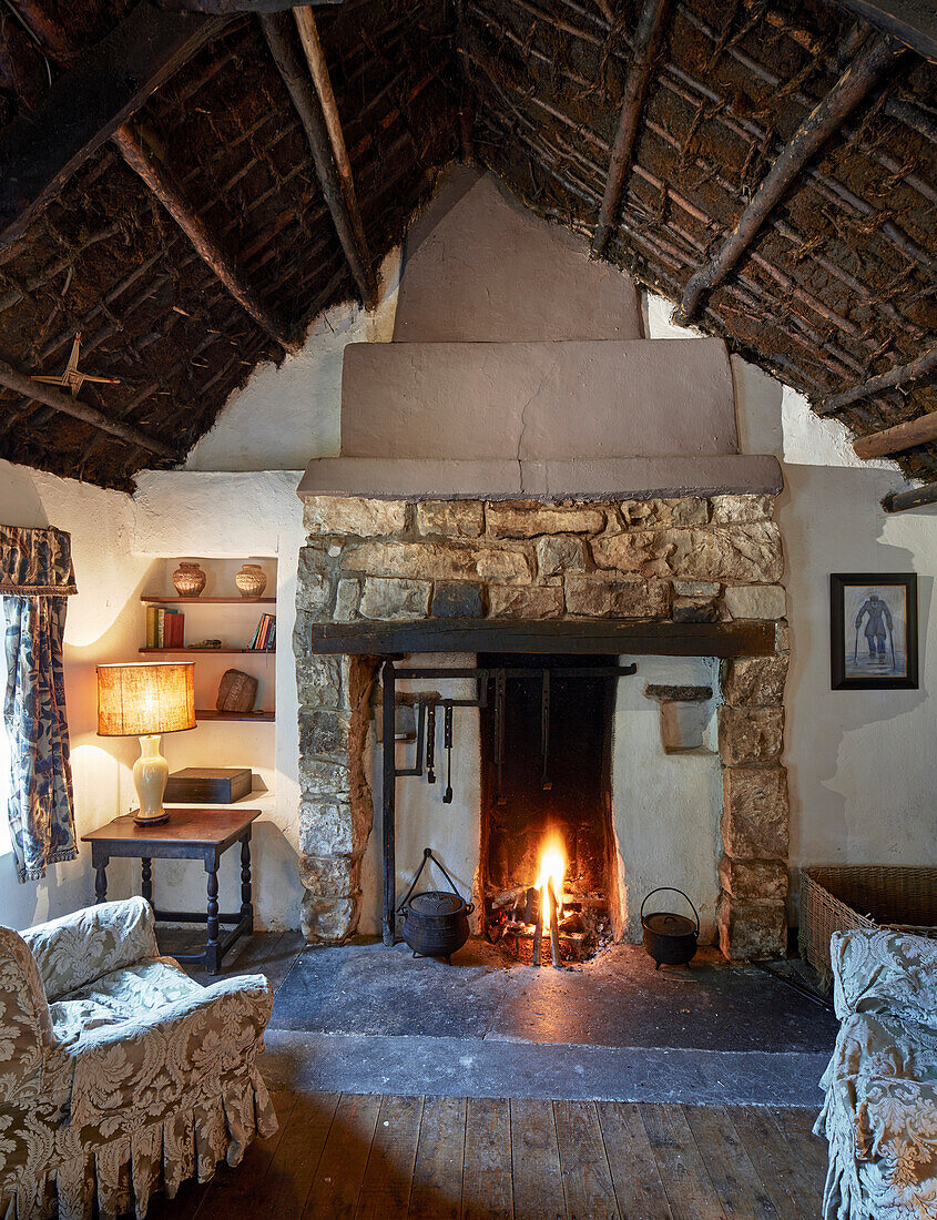 Rustic living room with fireplace and sod roof in traditional farmhouse, Ireland