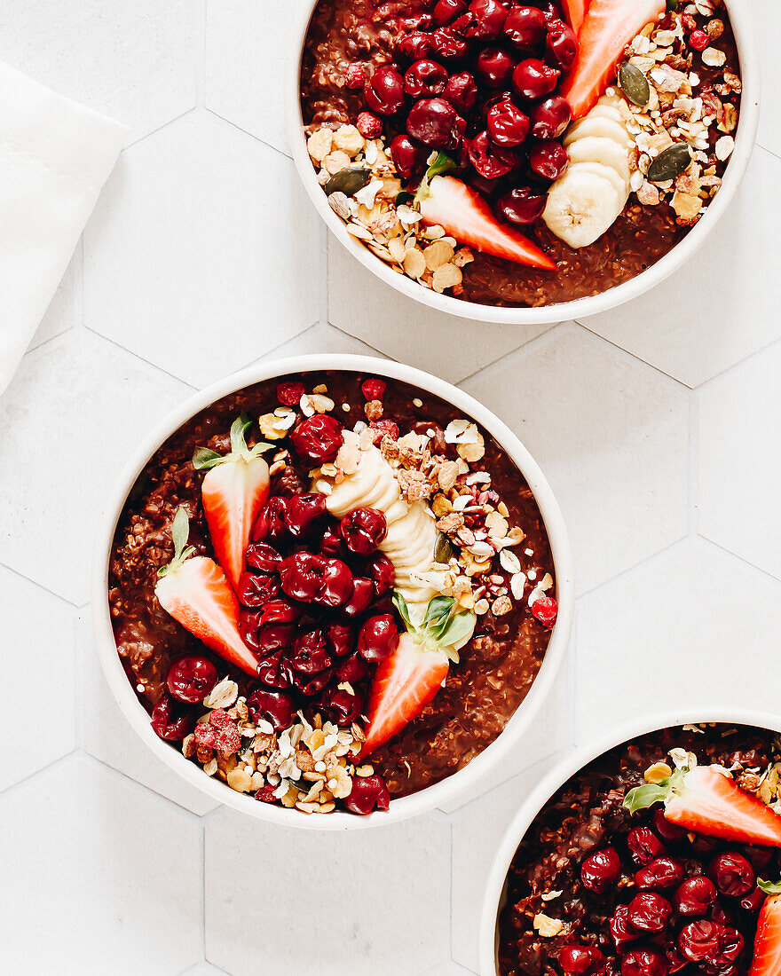 Chocolate porridge bowl with cherries, strawberries, granola and banana