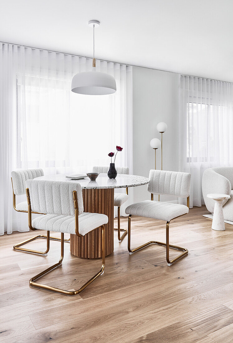 Dining room in 80s style with wooden column and marble dining table, and cream-colored bouclé chairs