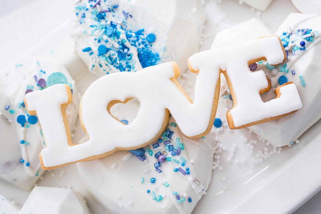 Heart cakes with white fondant and blue sugar sprinkles, and 'Love' biscuits