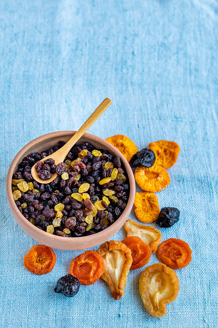 Dried fruits in a bowl and on a blue background