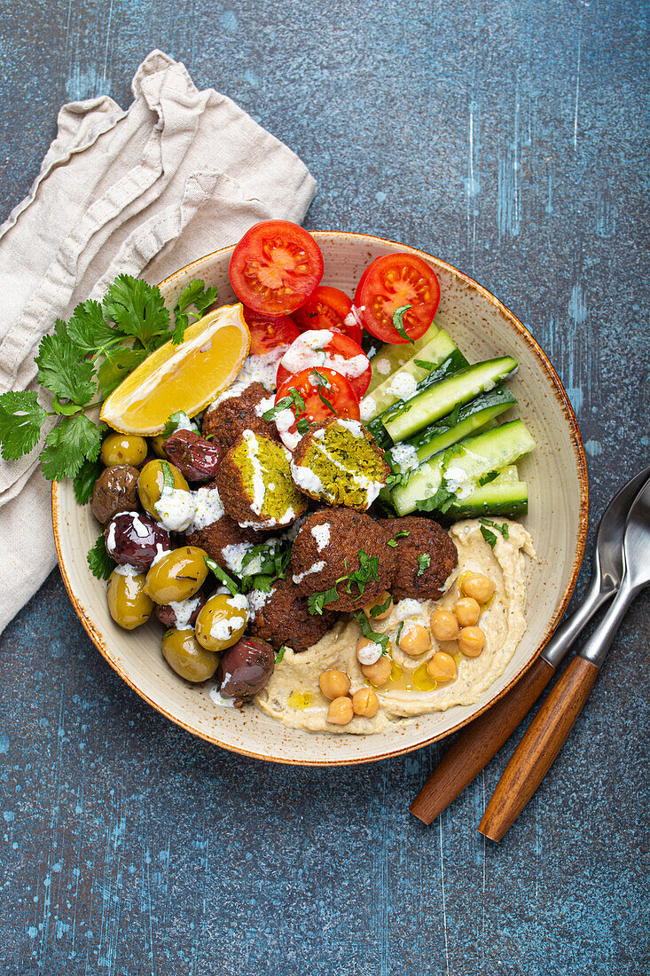 Falafel-Bowl mit Hummus, Gemüse, Oliven, Kräutern und Joghurtsauce