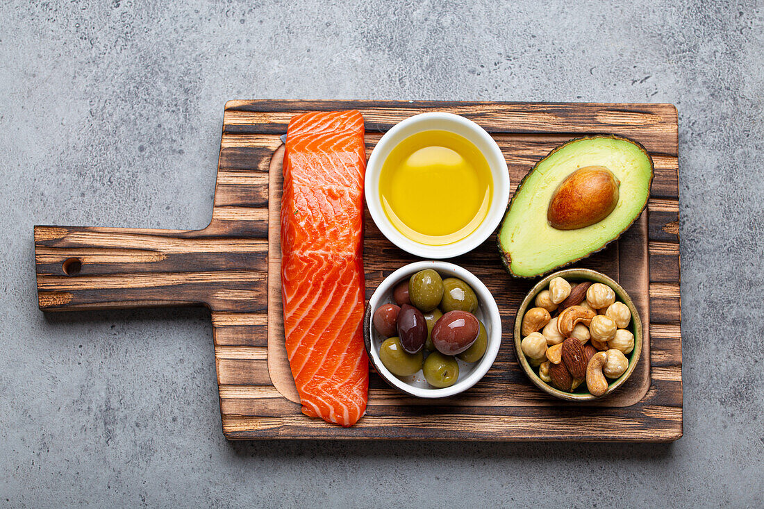 Food sources of healthy unsaturated fat: fresh salmon fillet, avocado, olives and nuts