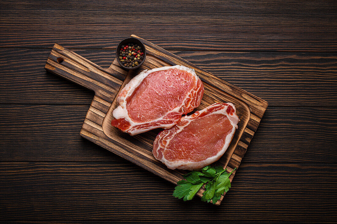 Raw pork steaks on a wooden board