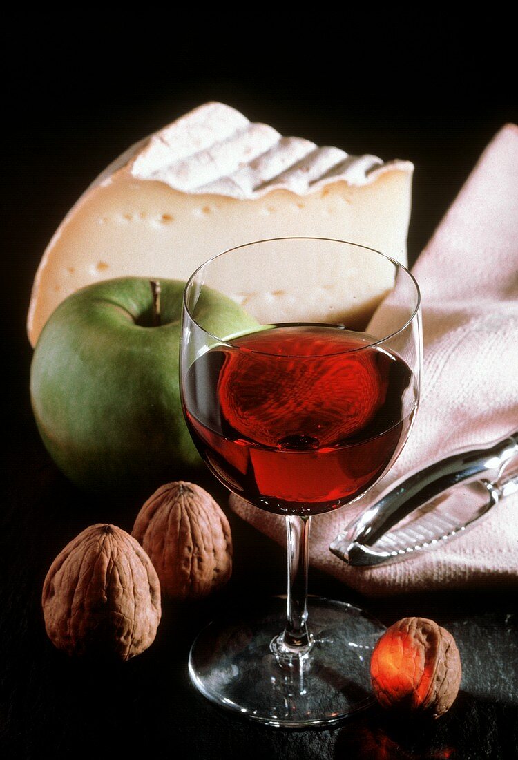 Ein Glas Rotwein, ein Stück Weichkäse, Nüsse & ein Apfel