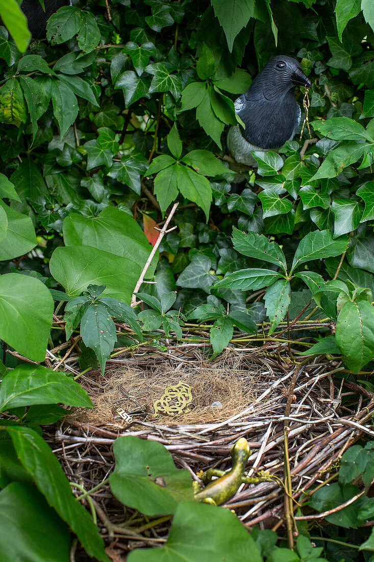 Vogelnest mit künstlicher Deko umgeben von Blättern