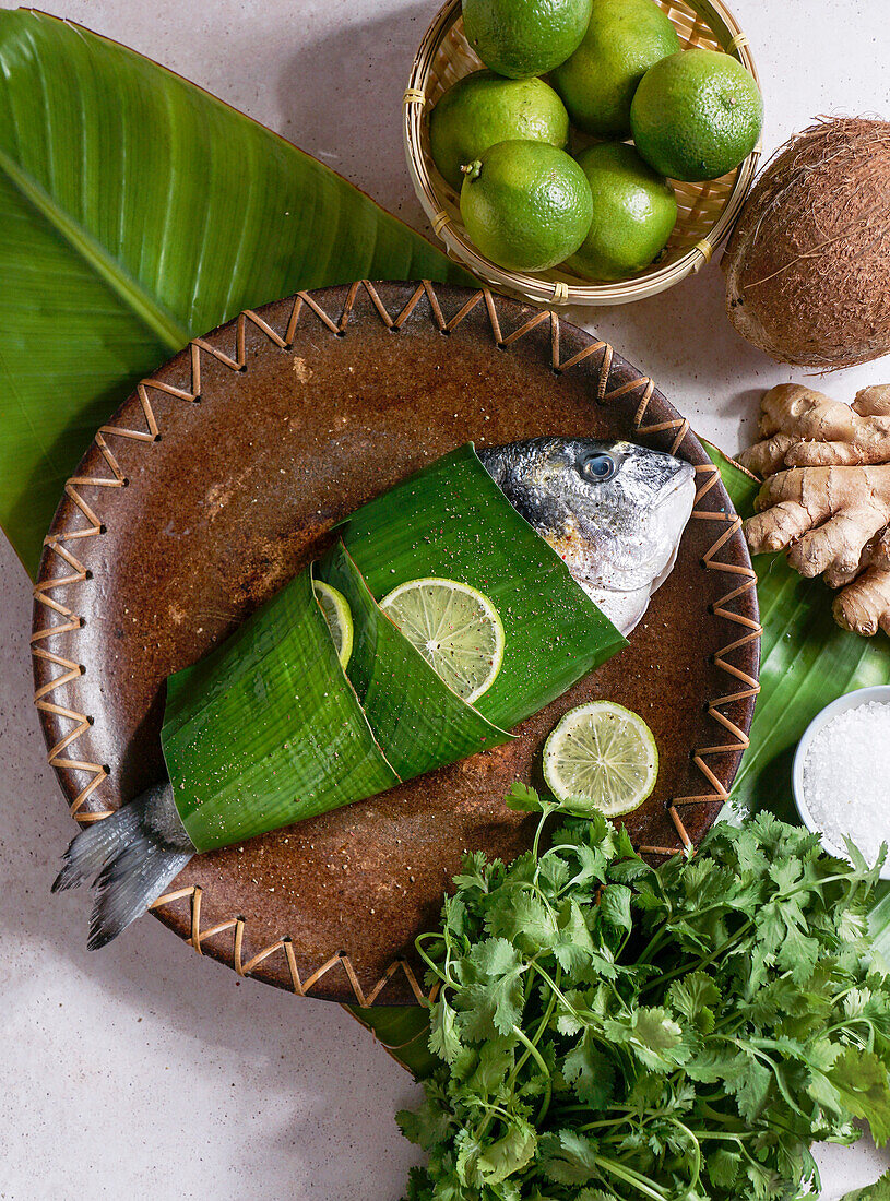 Frischer Fisch in Bananenblättern nach thailändischer Art mit Ingwer und Limette