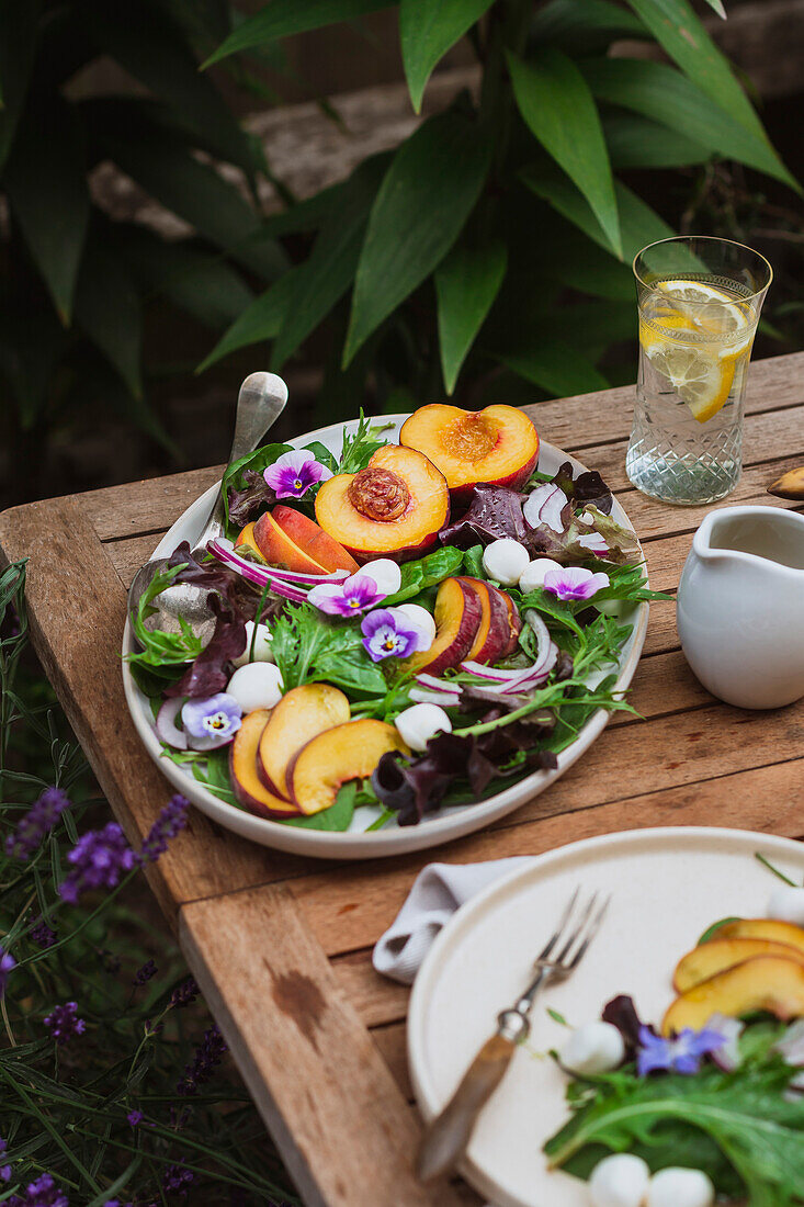 Summer salad with peach, mozzarella and violet flowers