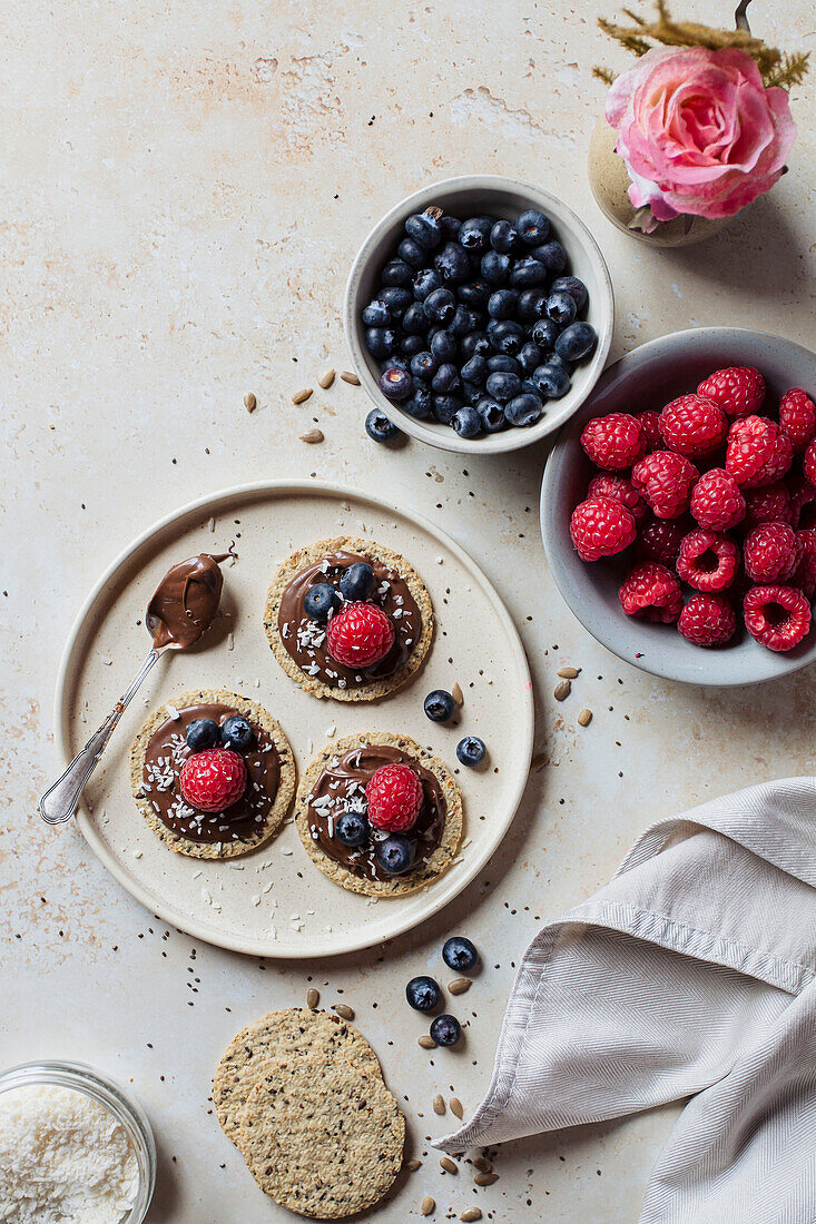 Oatcakes with chocolate spread, raspberries, blueberries and coconut flakes