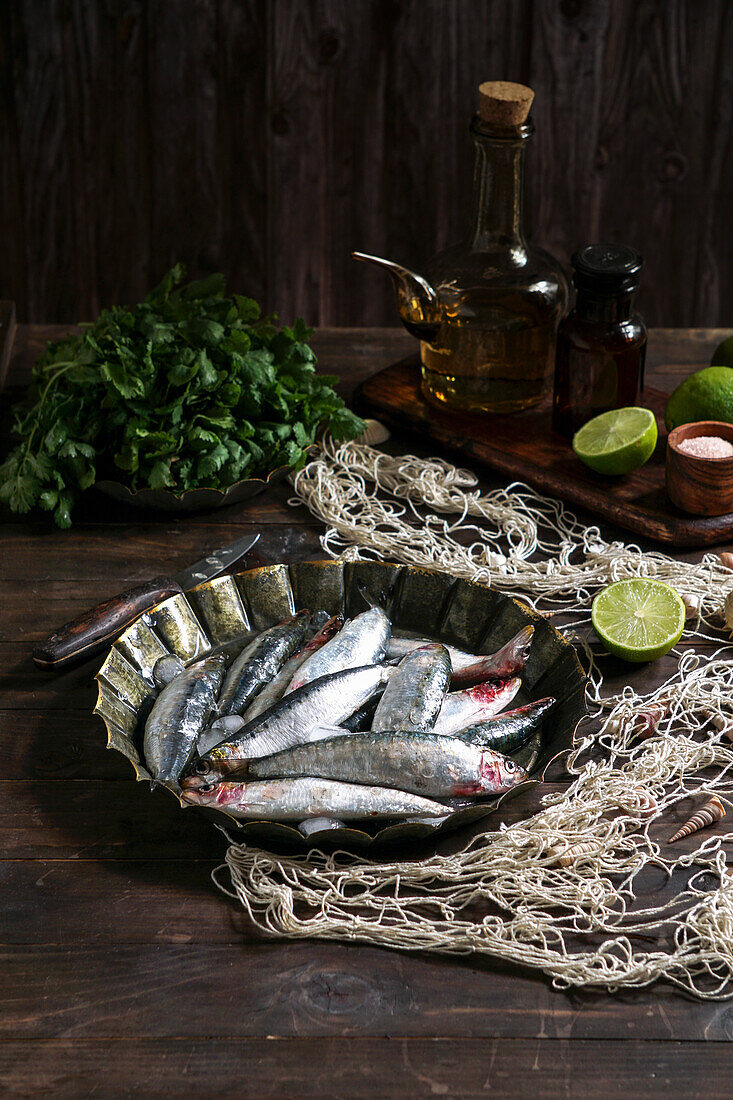 Fresh sardines with metal plate on rustic wooden background