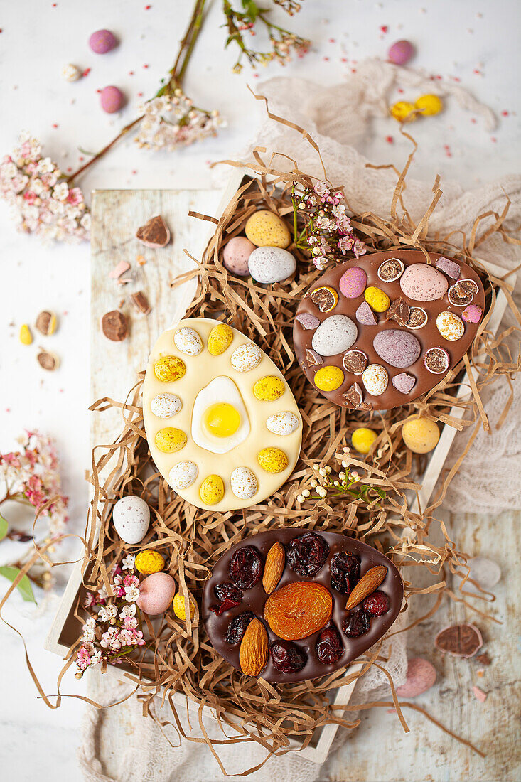 Schokoladen-Ostereier, dekoriert mit gemischten Bonbons, Nüssen und Trockenfrüchten