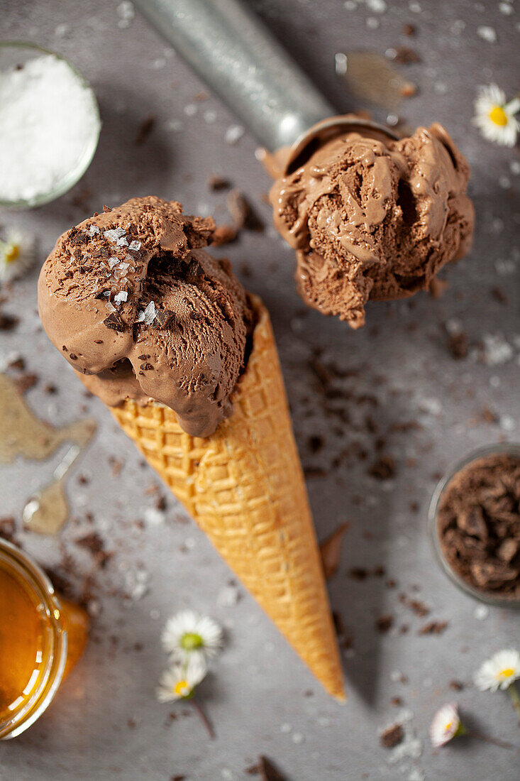 Chocolate ice cream with dark chocolate chips and sea salt flakes in a waffle cone