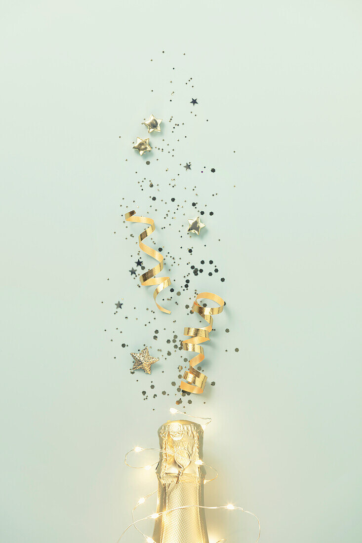 Champagne bottle with gold party streamers on blue background