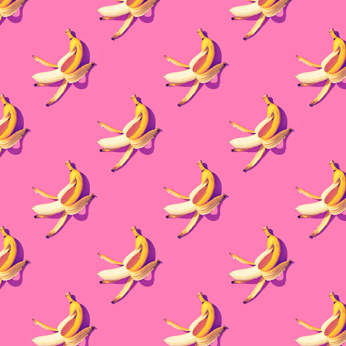 Ripe bananas, partly peeled, on a pink background