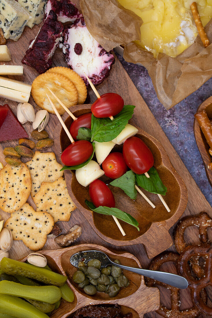 Appetizer board with caprese, crackers, cheese, fruit and pickles
