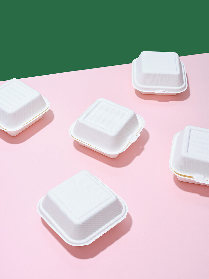 Take-Out Boxen für Burger vor grün-rosa Hintergrund