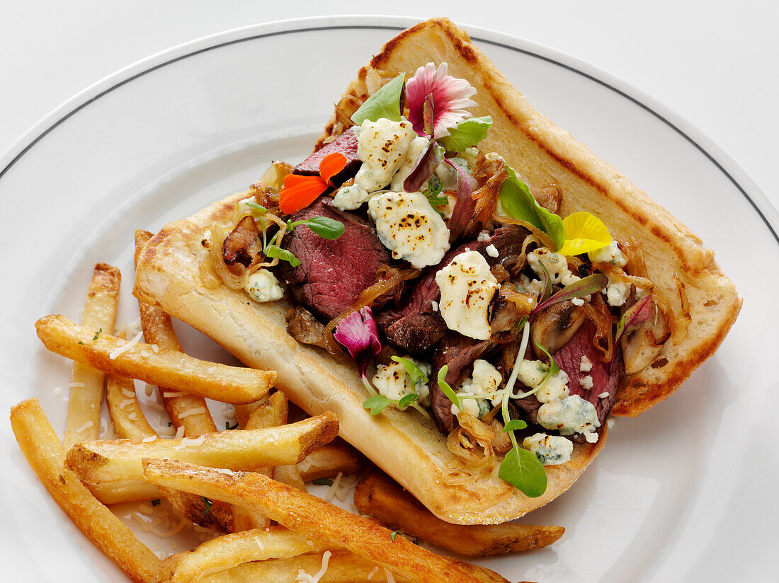 Gegrilltes Steak-Sandwich mit karamellisierten Zwiebeln und Blauschimmelkäse, dazu Parmesan-Pommes