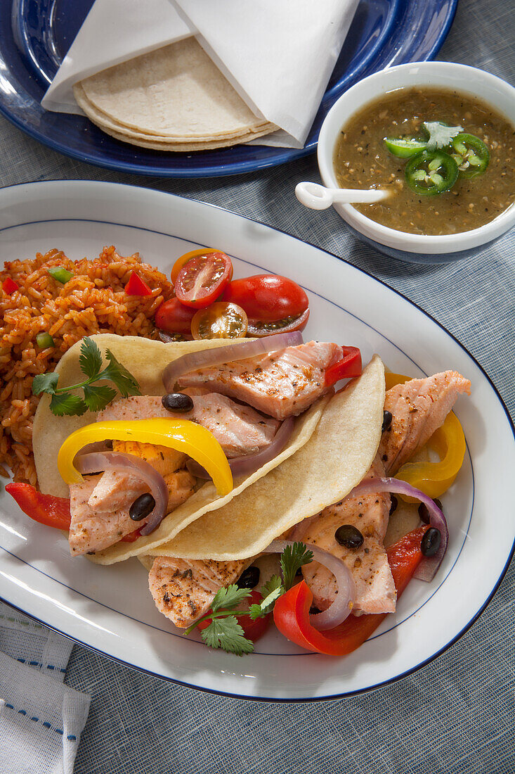 Lachs-Fajitas mit Paprika, schwarzen Bohnen, Kirschtomaten, spanischem Reis und Salsa Verde