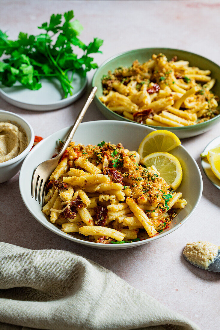 Hummus-Pasta mit Knusperbröseln, getrockneten Tomaten und Zitrone