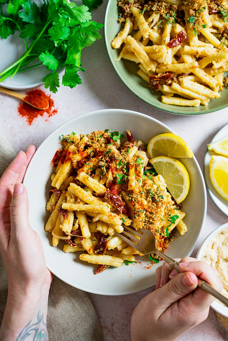 Hummus-Pasta mit Knusperbröseln, getrockneten Tomaten und Zitrone