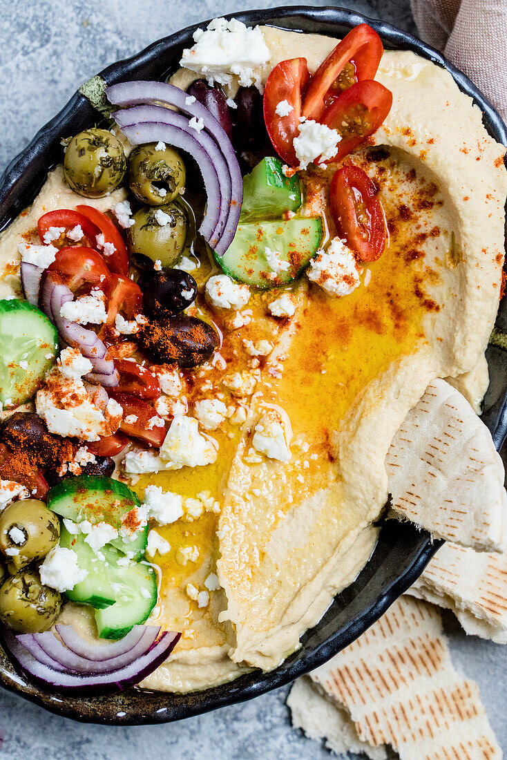 Loaded hummus platter with feta, tomatoes, cucumber, olives, and onions