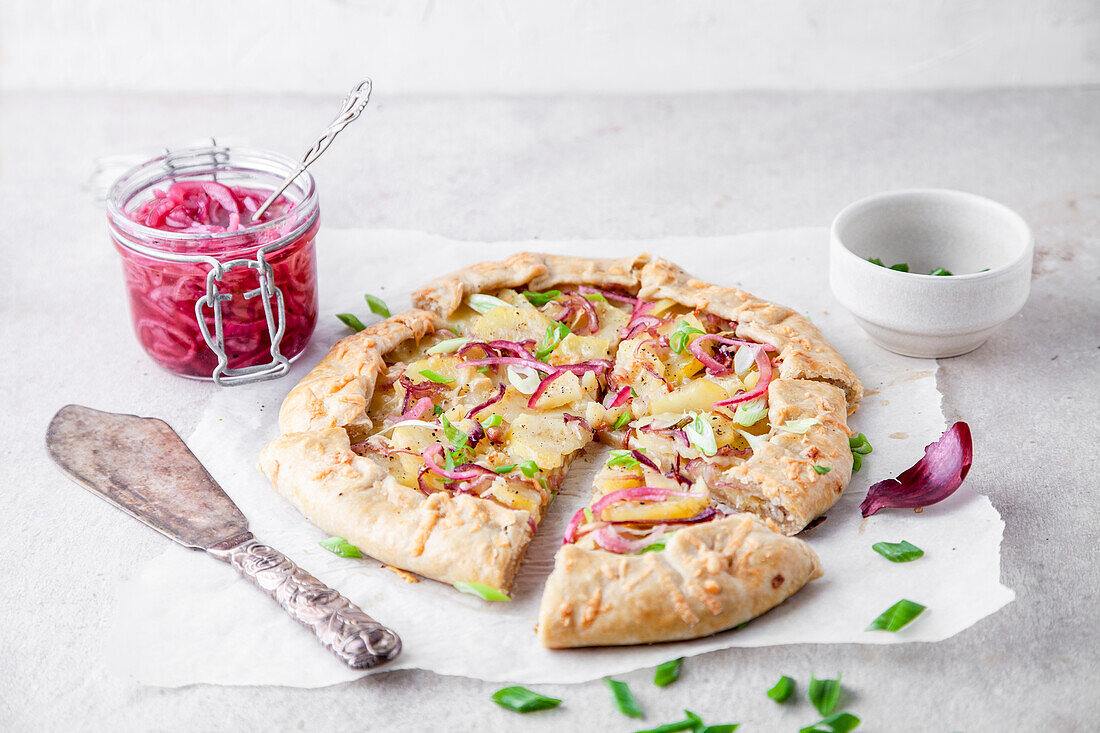 Kartoffelgalette mit eingelegten roten Zwiebeln und grünen Frühlingszwiebeln