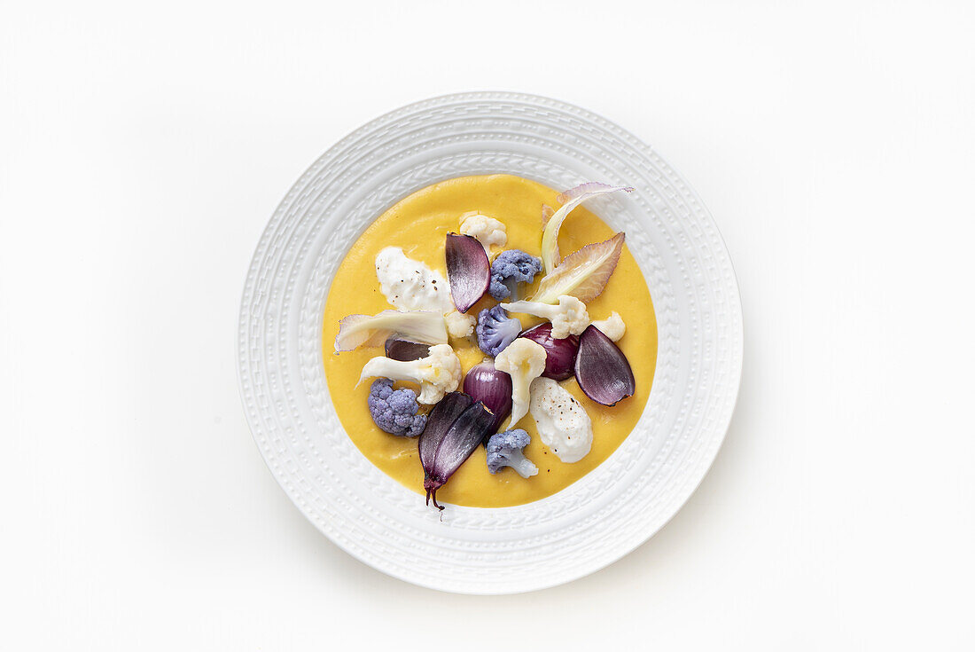 Gelbe Paprikacreme mit weißen und violetten Blumenkohlröschen, Zwiebeln und Burrata-Käse