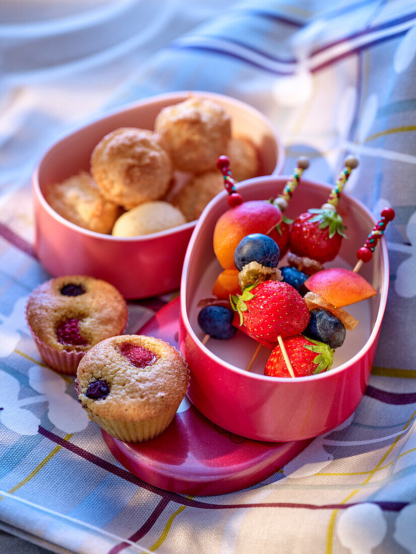 Fruchtspieße und Muffins mit Beeren