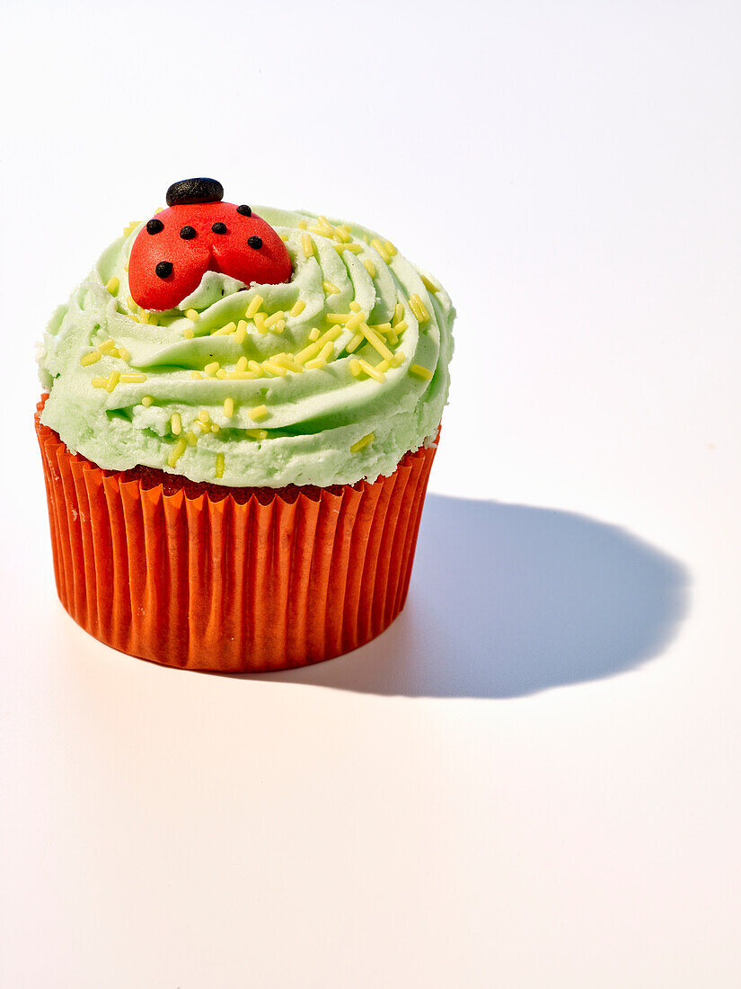 Cupcake mit grünem Frosting und Marzipan-Marienkäfer