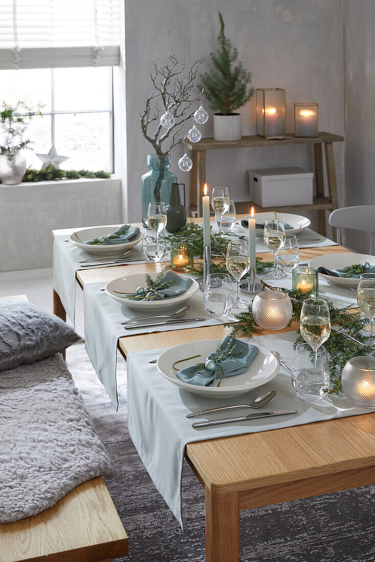 Festively laid dining table with light blue accents and candlelight in winter