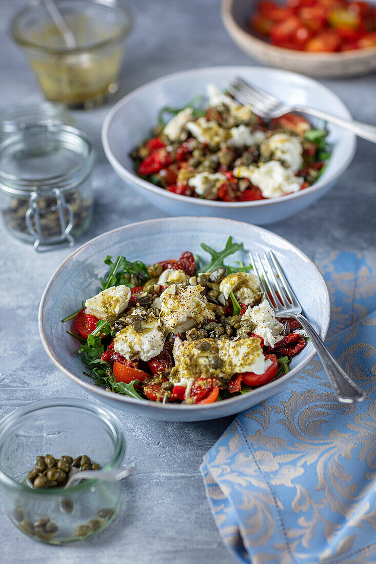 Tomaten-Mozzarella-Salat mit getrockneten Tomaten, Rucola und Kapern