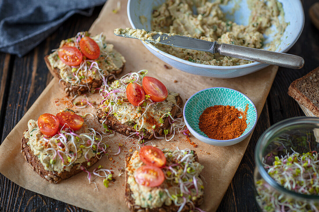 Bread with avocado bean spread, sprouts, and tomatoes