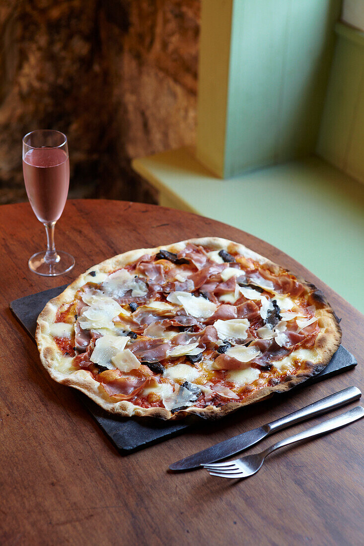 Prosciutto-Funghi-Pizza serviert mit Prosecco