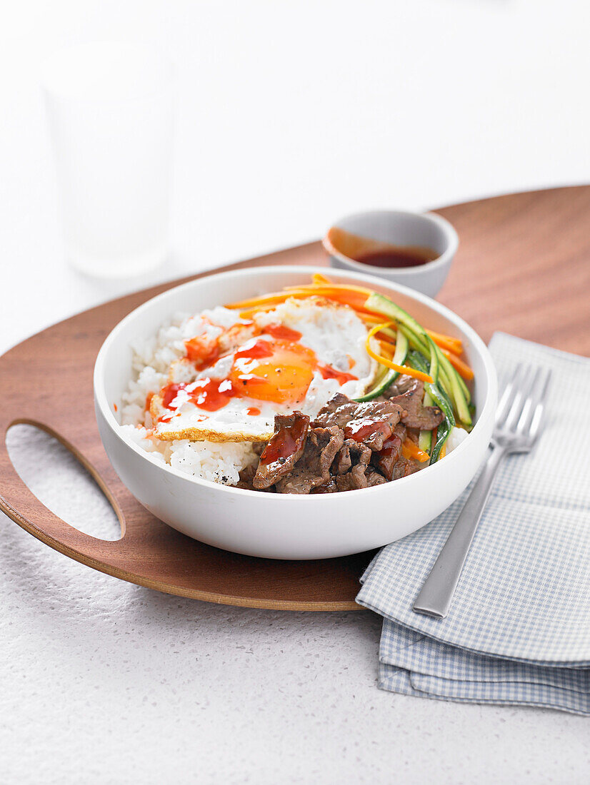 Sushi-Reis-Bowl mit Rindfleisch, Spiegelei und Chilisauce