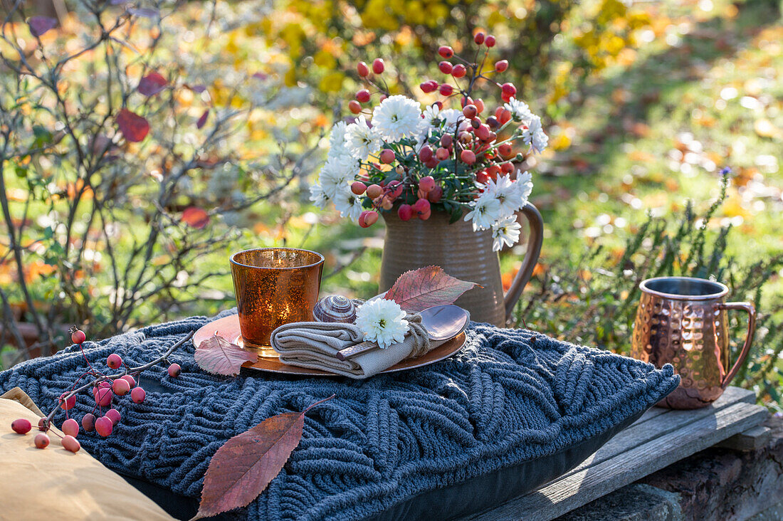 Herbstlicher Gartentisch mit Blumenstrauß aus Zierapfel und Chrysanthemen (Chrysanthemum)