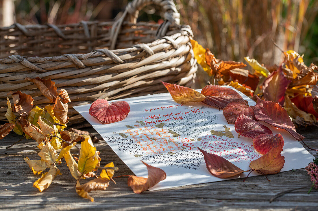 Herbstlaub und handgeschriebene Gedichte auf Gartentisch