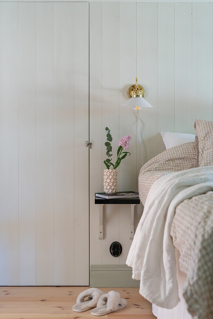 Wall-mounted bedside table with flower vase in the bedroom