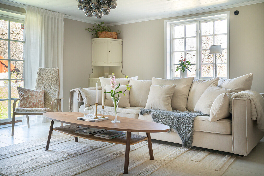 Living room with beige sofa, wooden table, flowers and candles