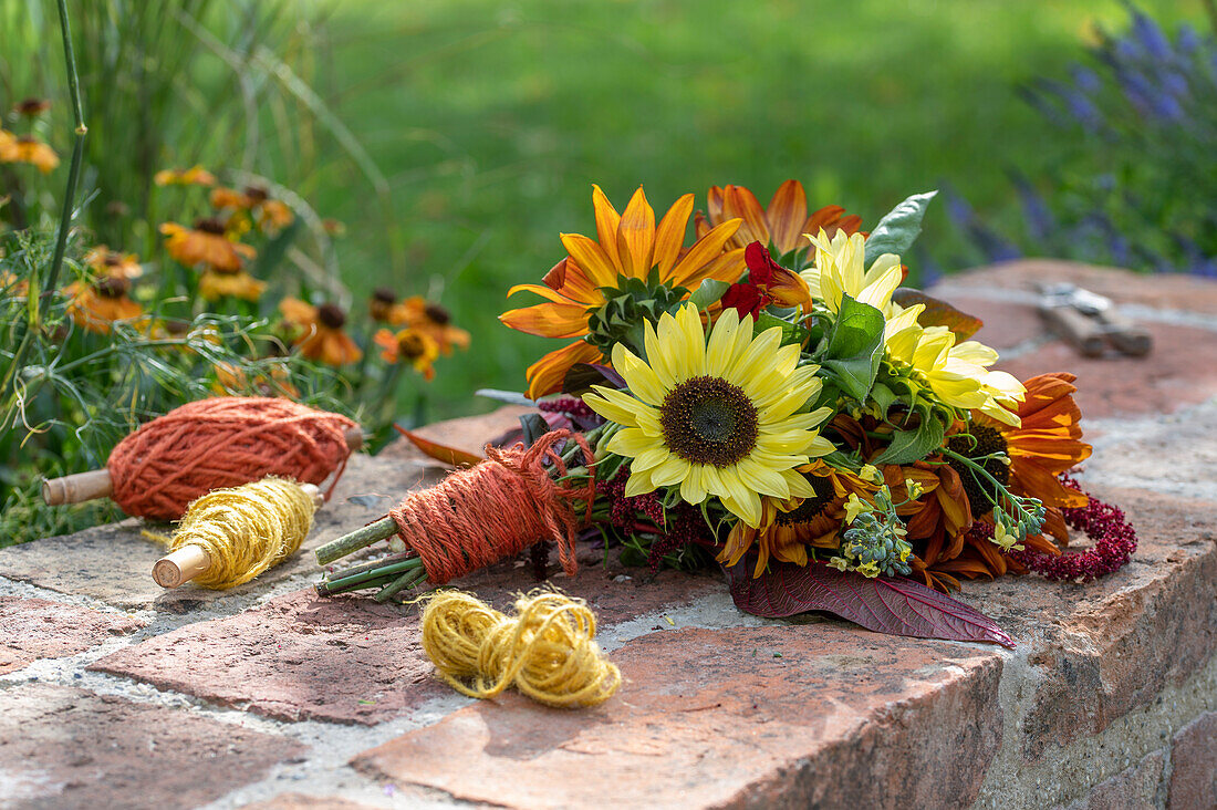 Bouquet with sunflowers (Helianthus), broccoli, foxtail Amaranth (Amaranthus) on garden wall and twine