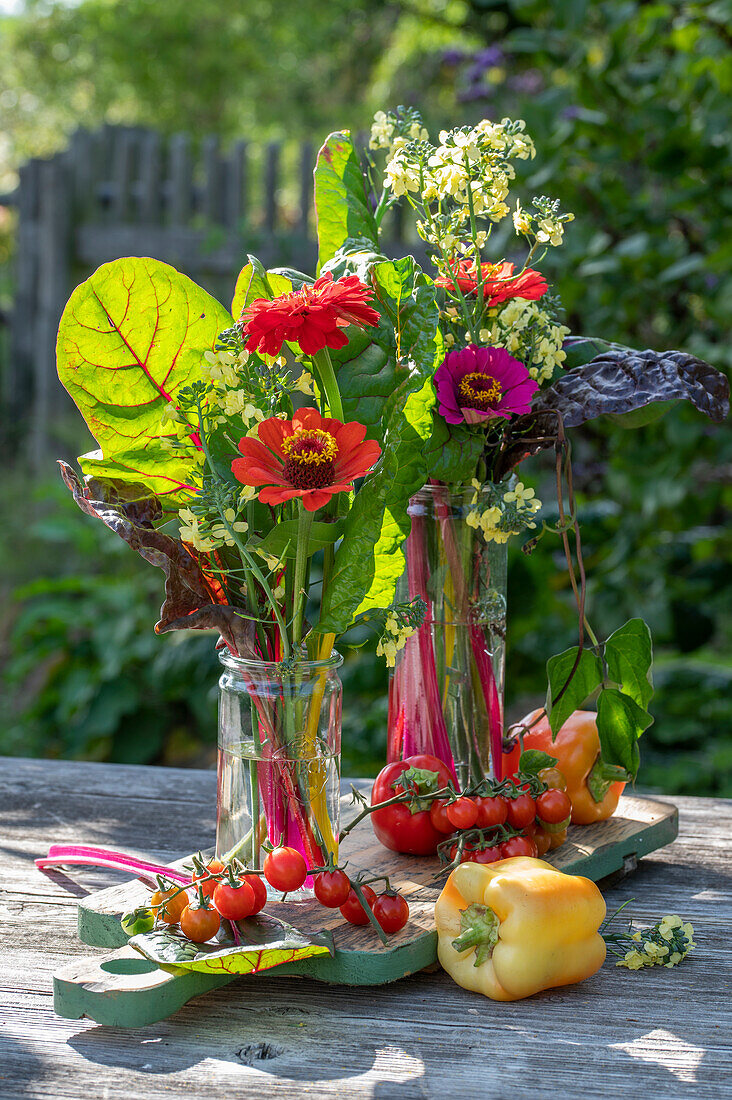 Tischdeko mit Blumenstrauß aus Zinnen (Zinnia) und Mangoldblättern, Brotzeitbrett mit Tomaten, Paprika