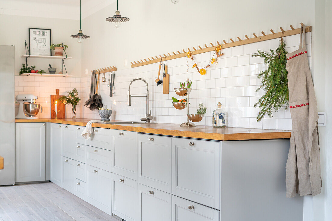 Scandinavian-style kitchen with light grey cabinets, wooden counter and metro tiles