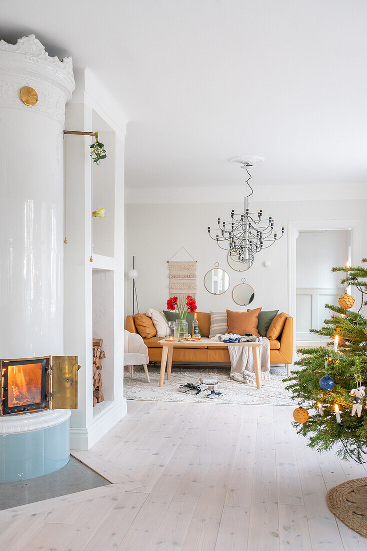 Bright living room with fireplace, Christmas tree and metallic chandelier