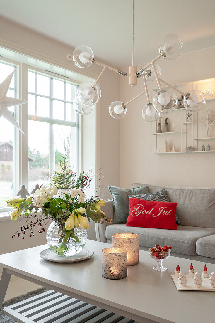 Living room decorated for Christmas with modern ceiling light and flower arrangement