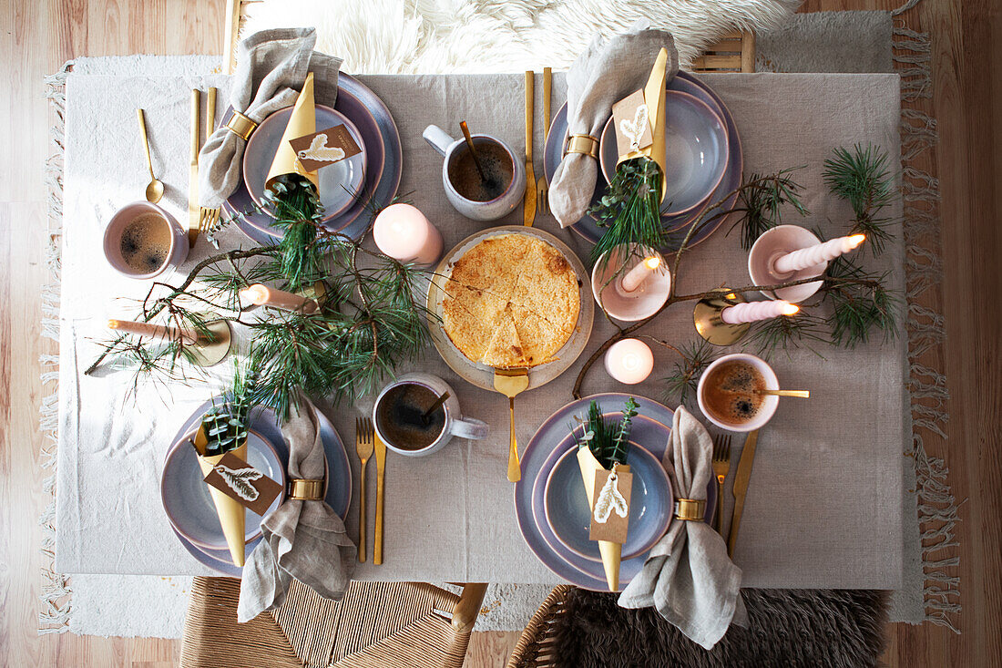 Festive table setting with gold-coloured cutlery and fir branches